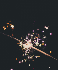 A sparkler with embers flying against a dark sky